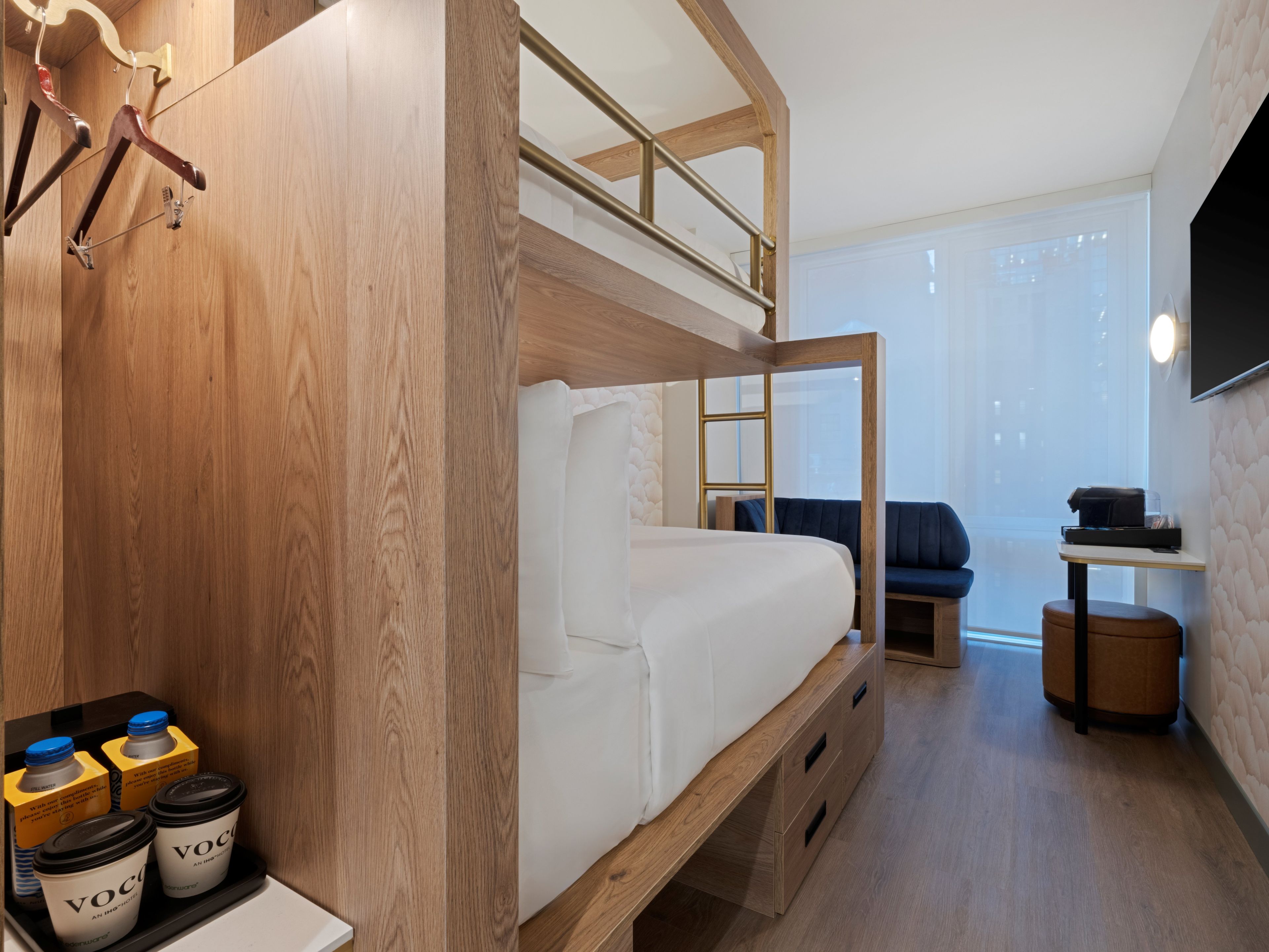 Habitación con literas, cabecero de madera, escritorio, silla y televisor en la pared.