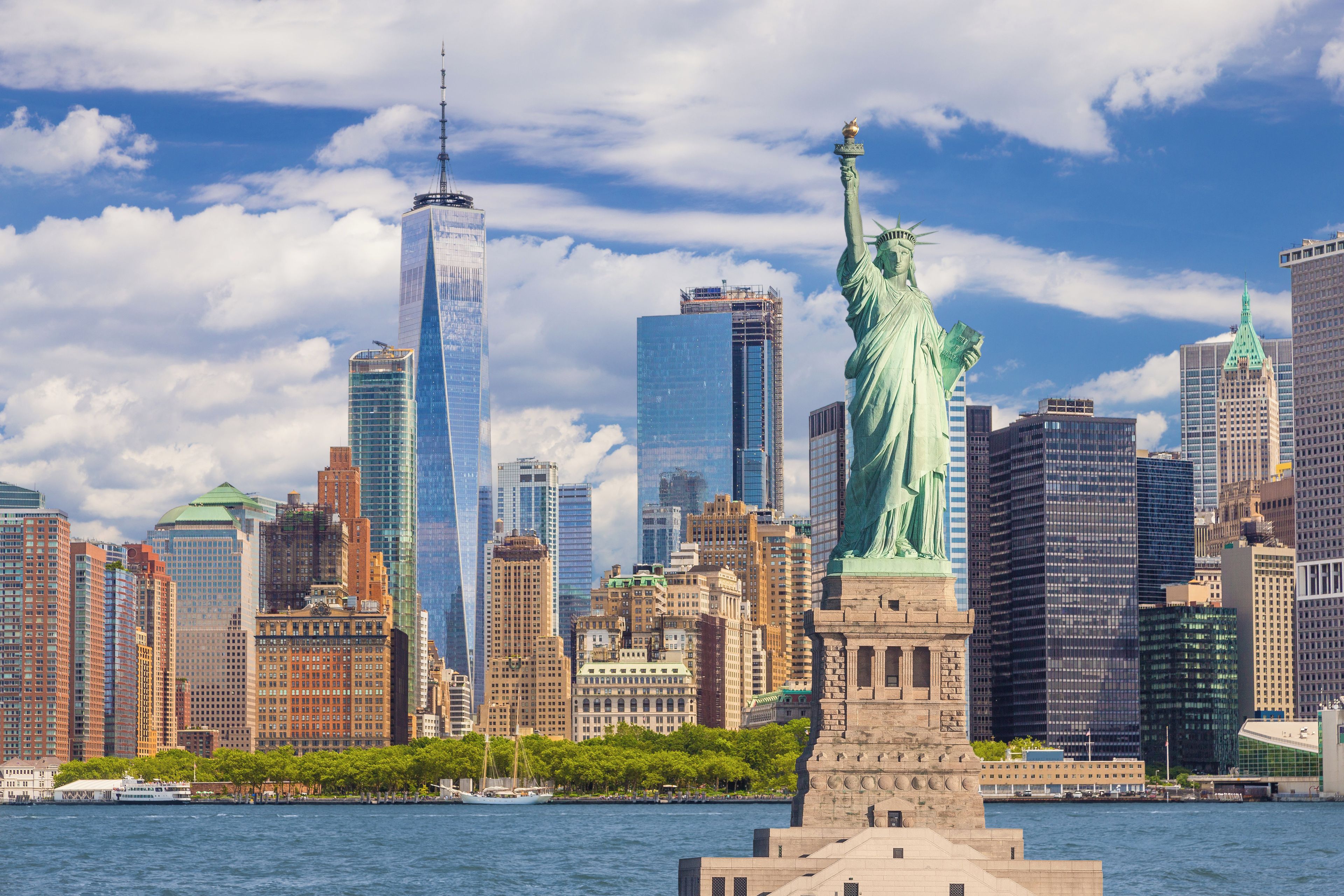 A city skyline with the Statue of Liberty in the foreground and modern skyscrapers in the background.