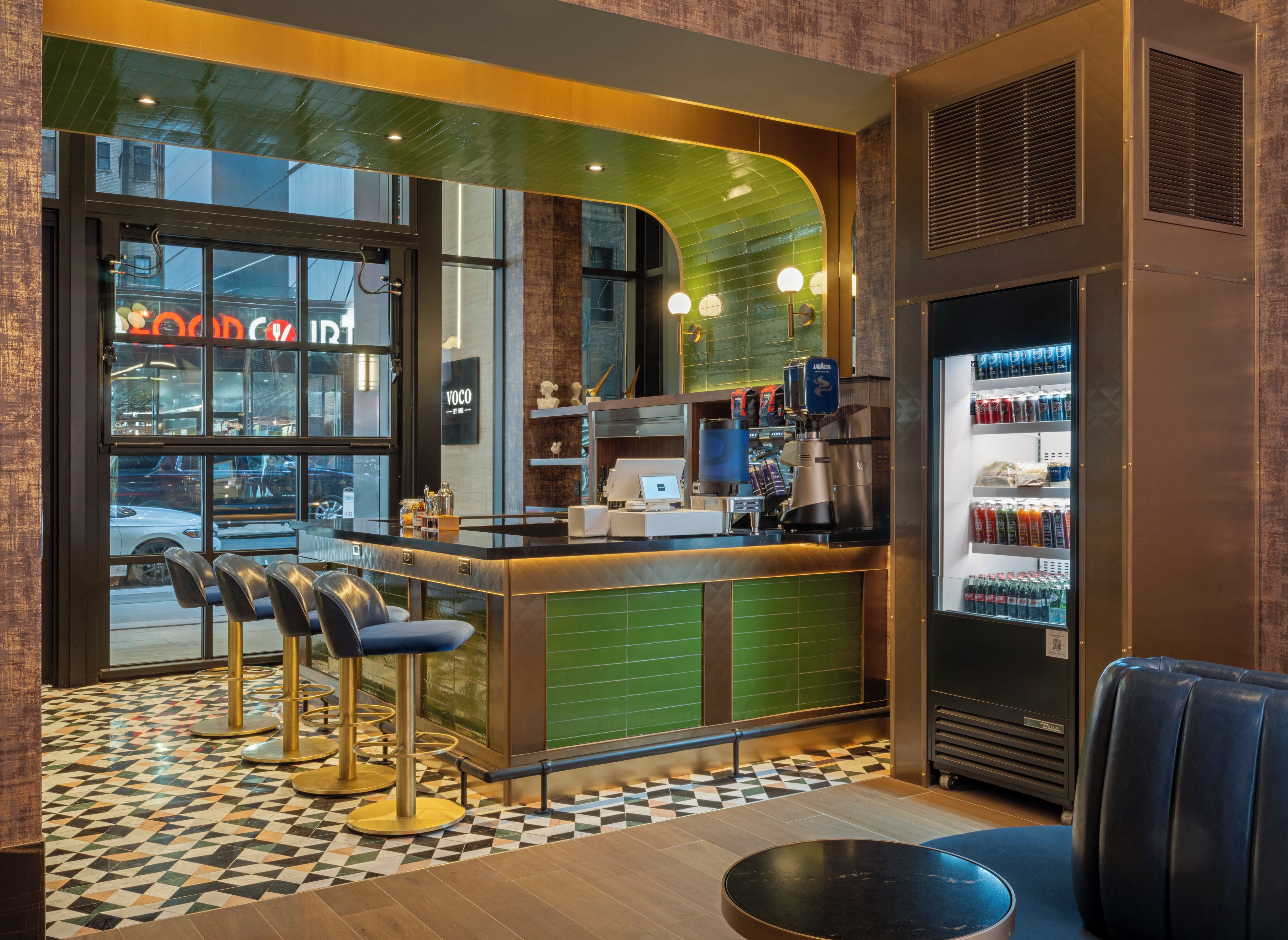 Interior de una cafetería con mostrador, zona de mesas y dispensador de bebidas.