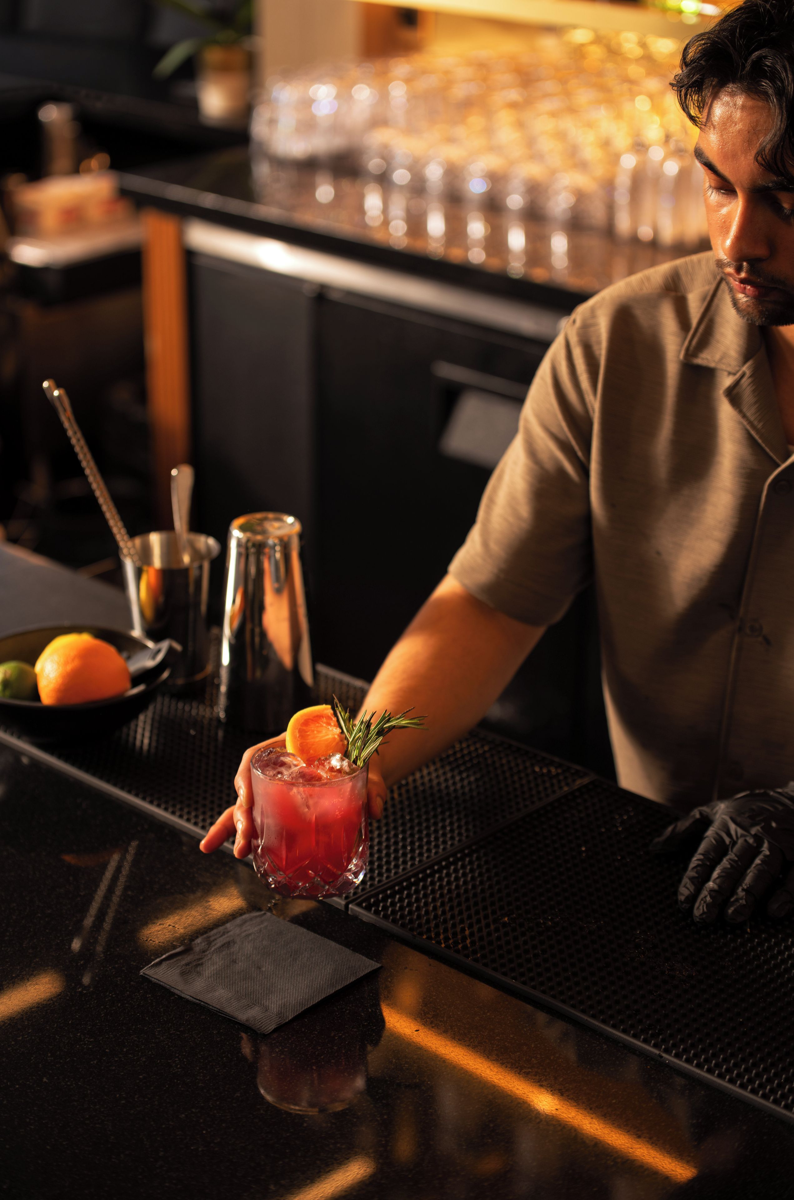 Um balcão de bar com um barman preparando uma bebida.