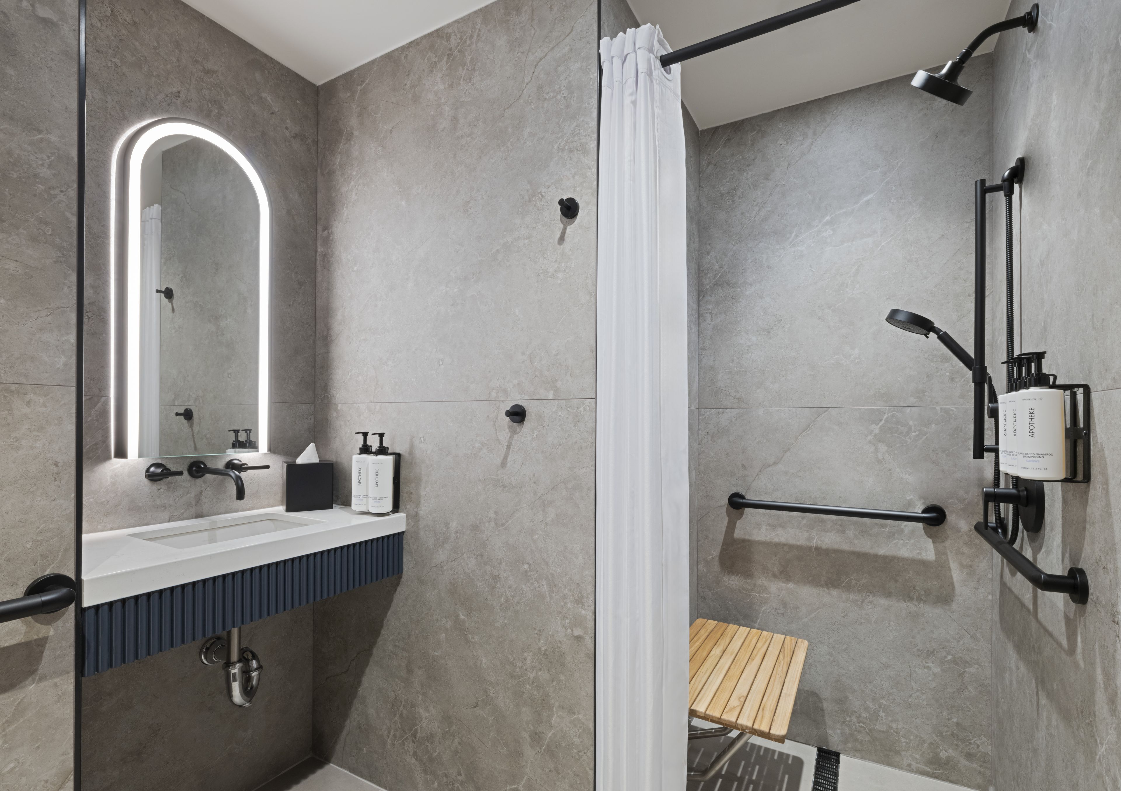 Un baño moderno con ducha, lavabo con espejo y un perchero para toallas.