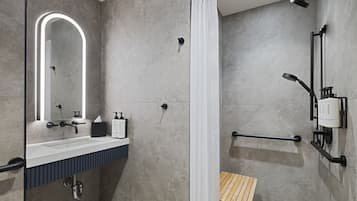 Un baño moderno con ducha, lavabo con espejo y un perchero para toallas.