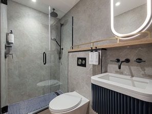A modern bathroom with a glass-enclosed shower, a toilet, and a sink with a vanity. - voco Times Square - Broadway by IHG (New York)