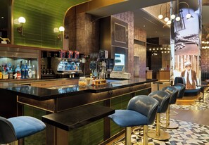 Área de bar moderna com balcão, banquetas e diversos tipos de bebidas.