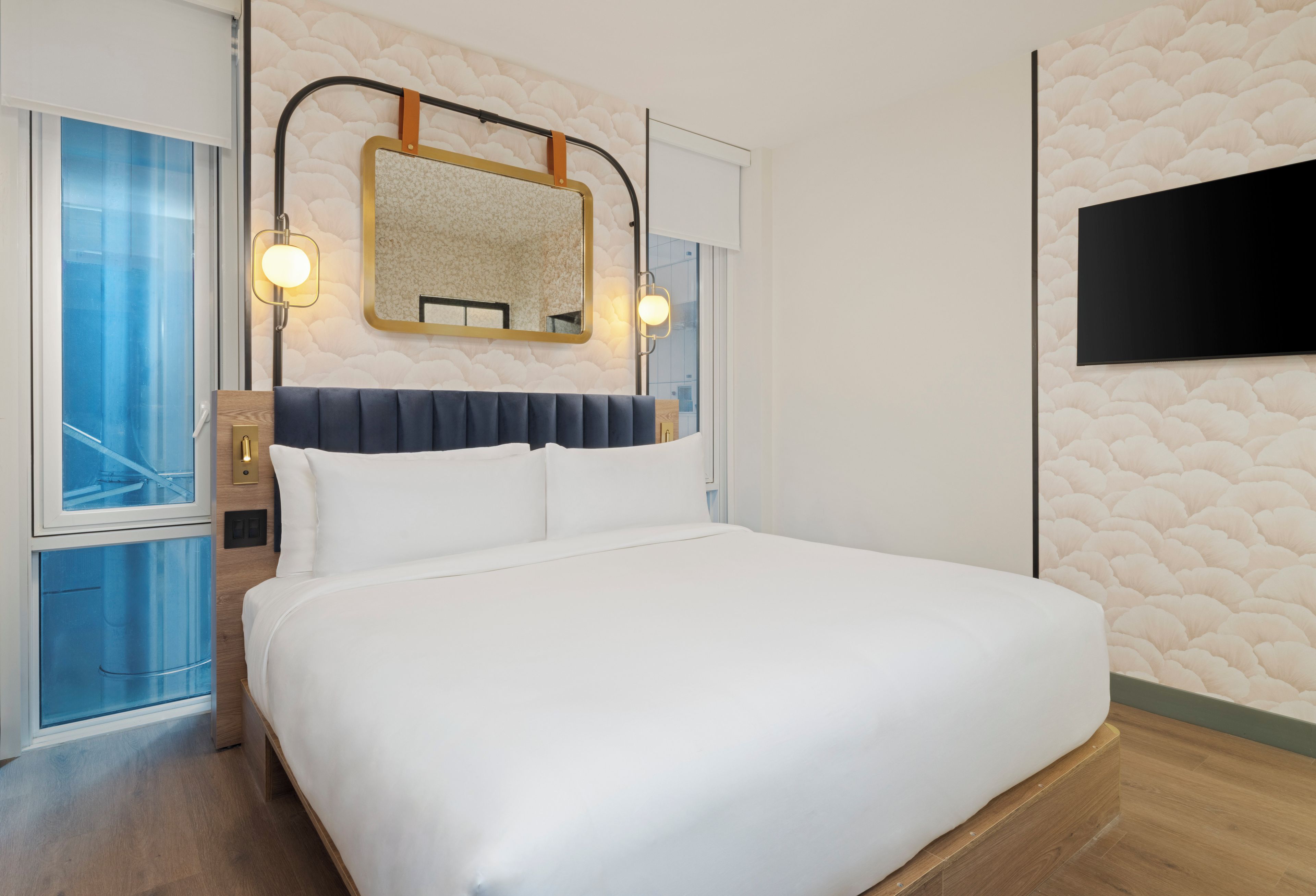 Ein Hotelzimmer mit Bett, Wandfernseher und Fenster mit Blick.