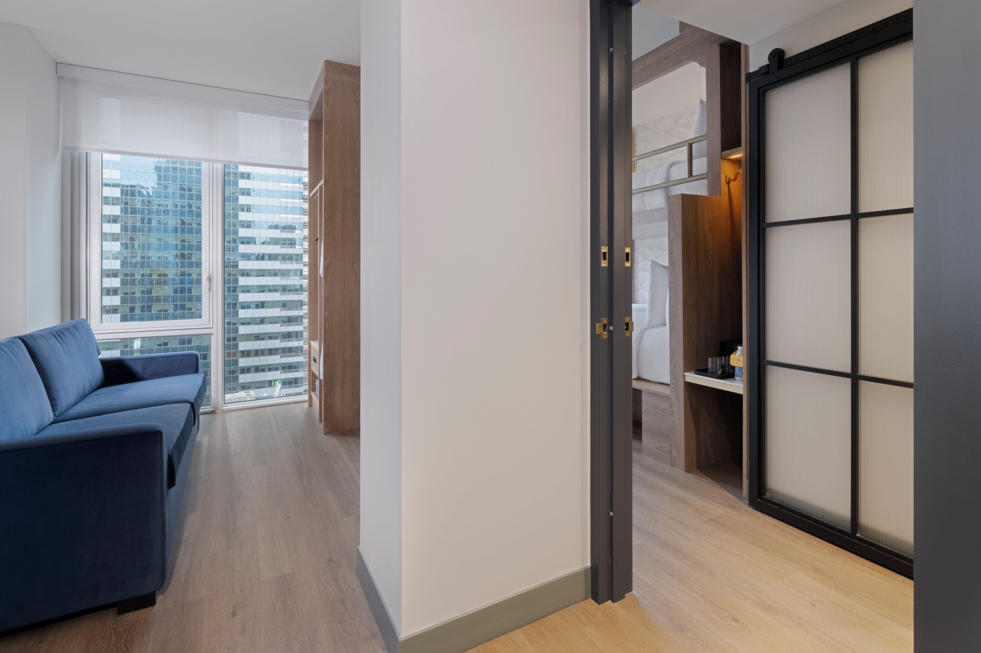 A modern interior with a sofa, a sliding door, and a view of buildings.