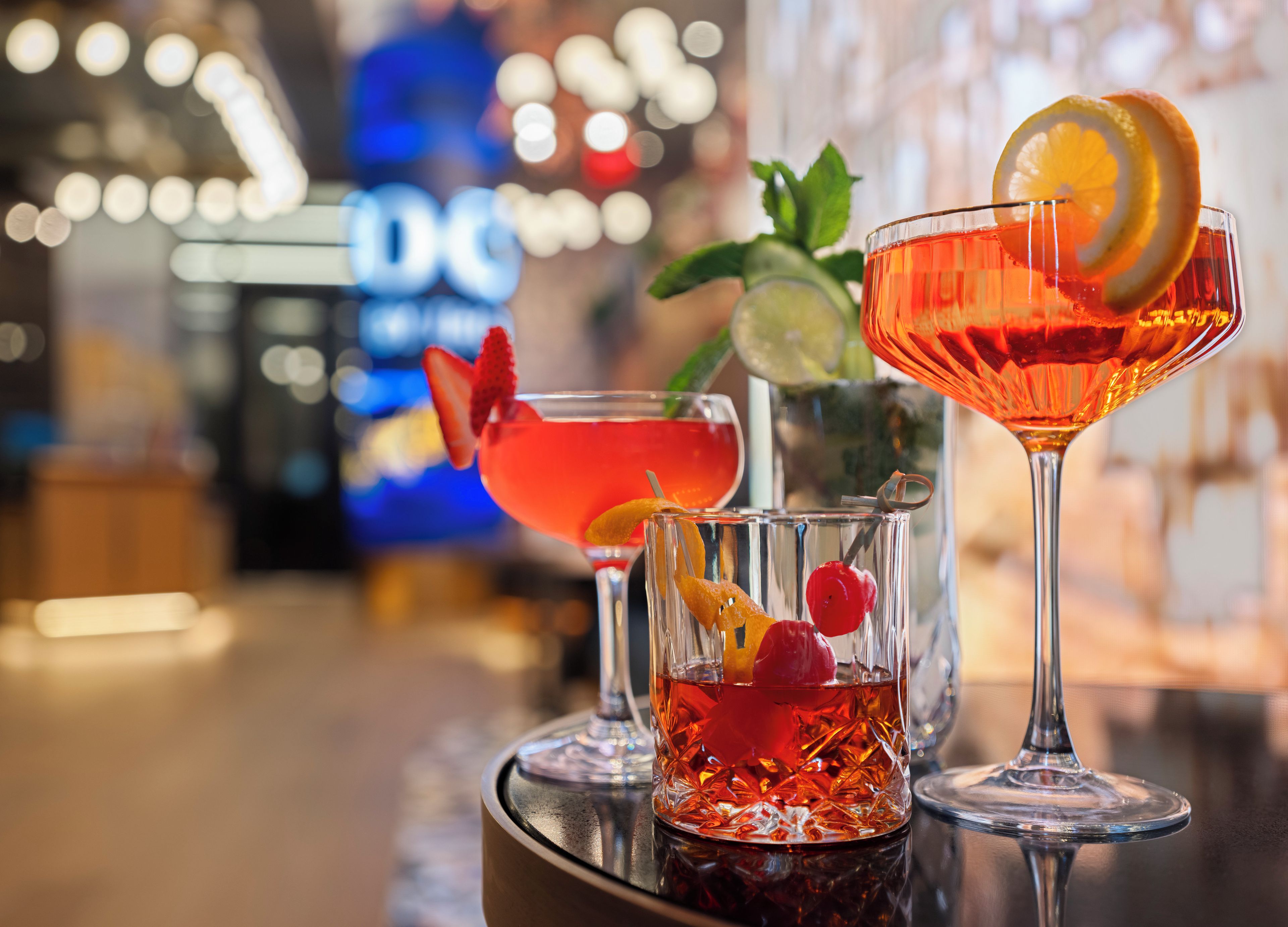 Trois cocktails sur le comptoir d’un bar, avec un arrière-plan flou.