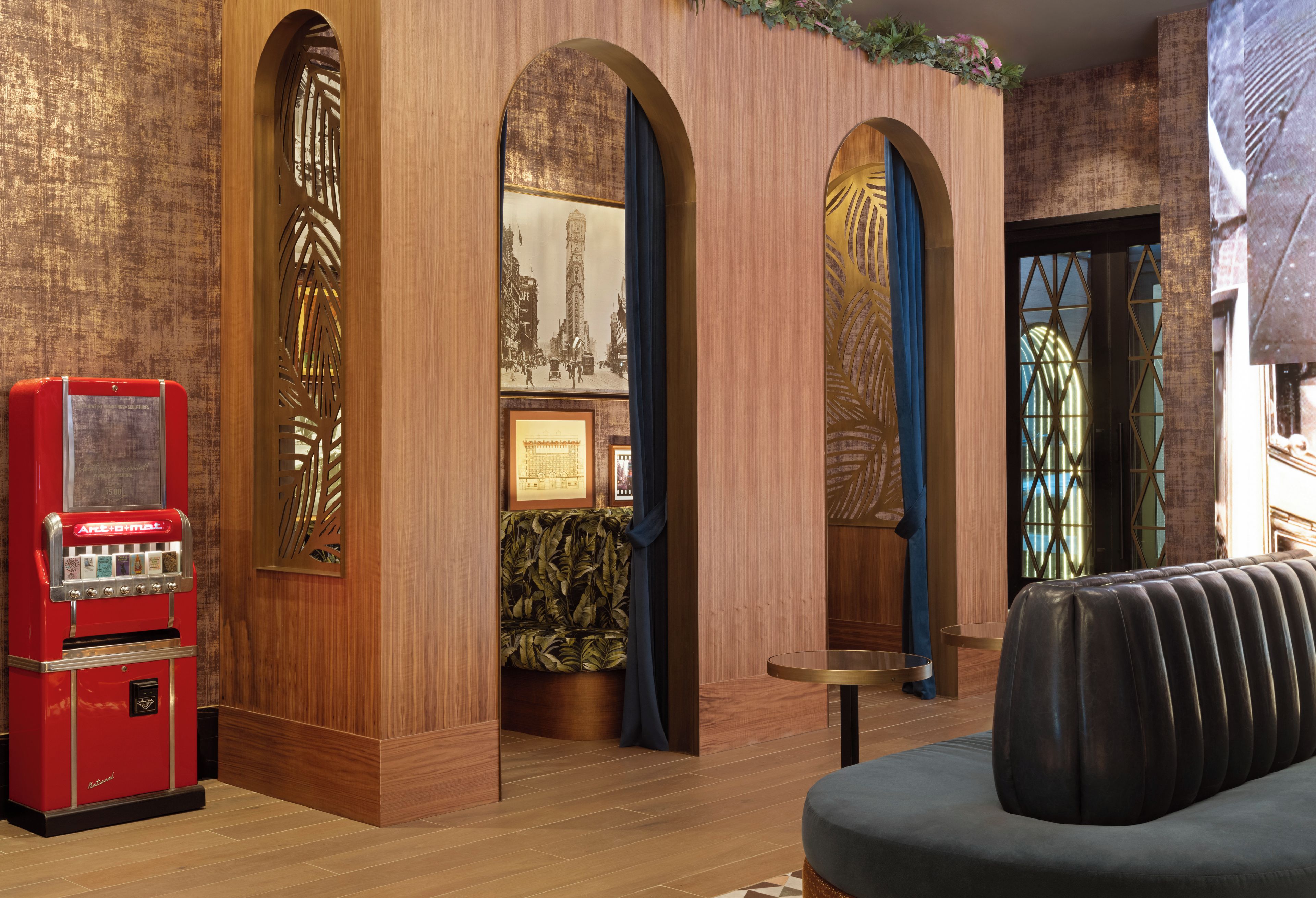 Eine Lobby mit Holzvertäfelung, einer roten Verkaufsmaschine im Vintage-Stil und einer Sitzecke mit einem gemusterten Sofa.