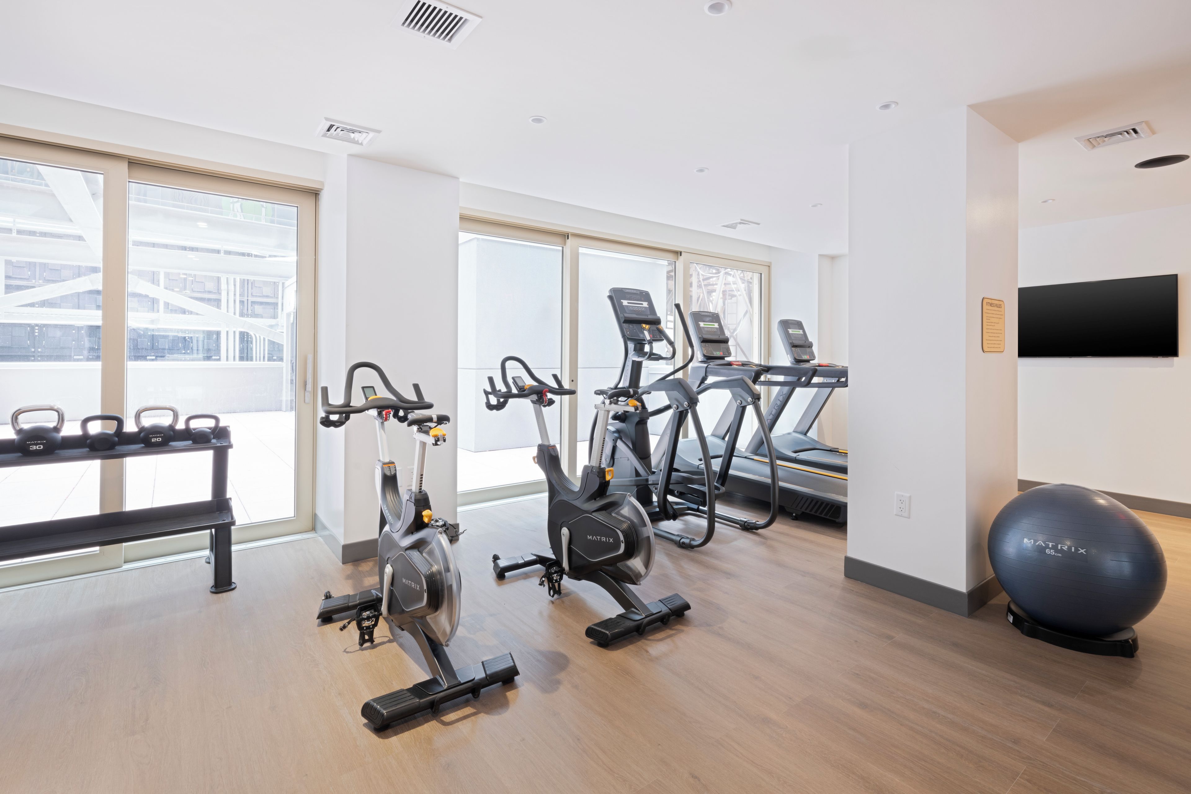 A gym with cardio machines, free weights, and a large exercise ball.