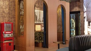 Una habitación con paneles de madera, una máquina expendedora roja de estilo vintage, un sofá estampado y una pequeña mesa redonda.