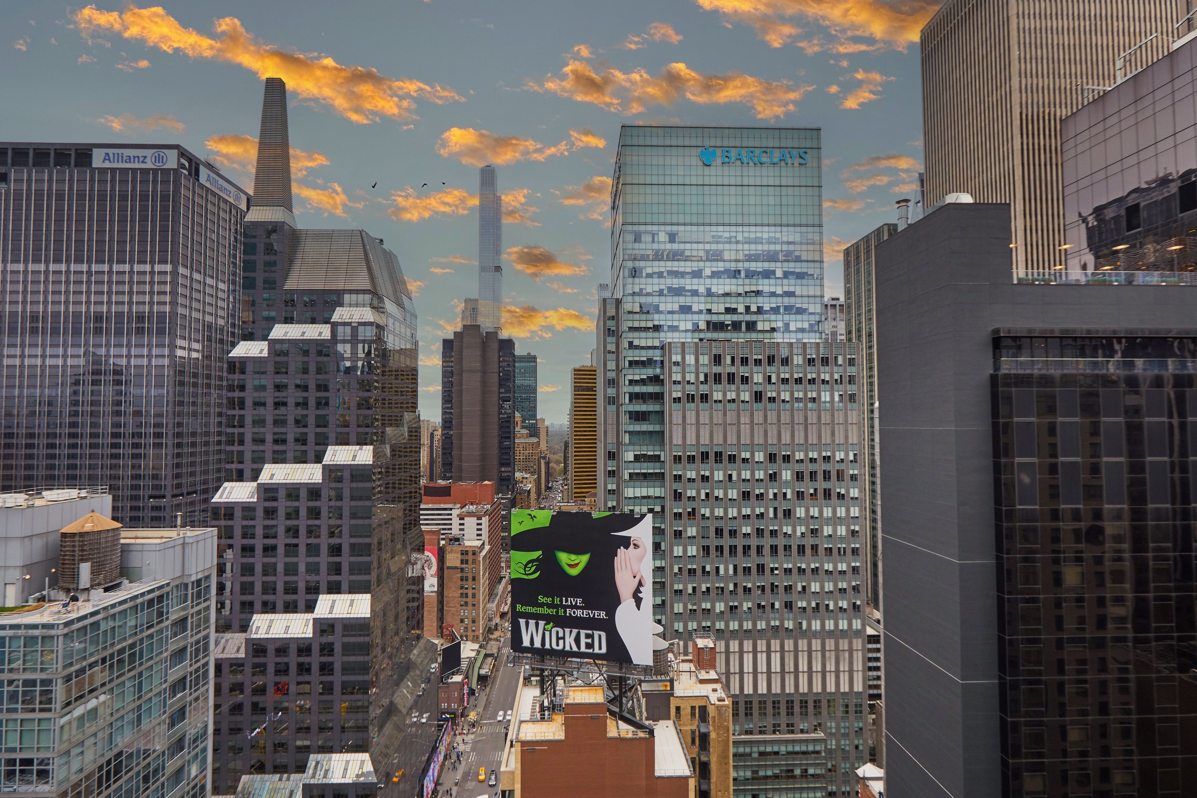A cityscape with modern buildings and a large billboard advertising a movie.