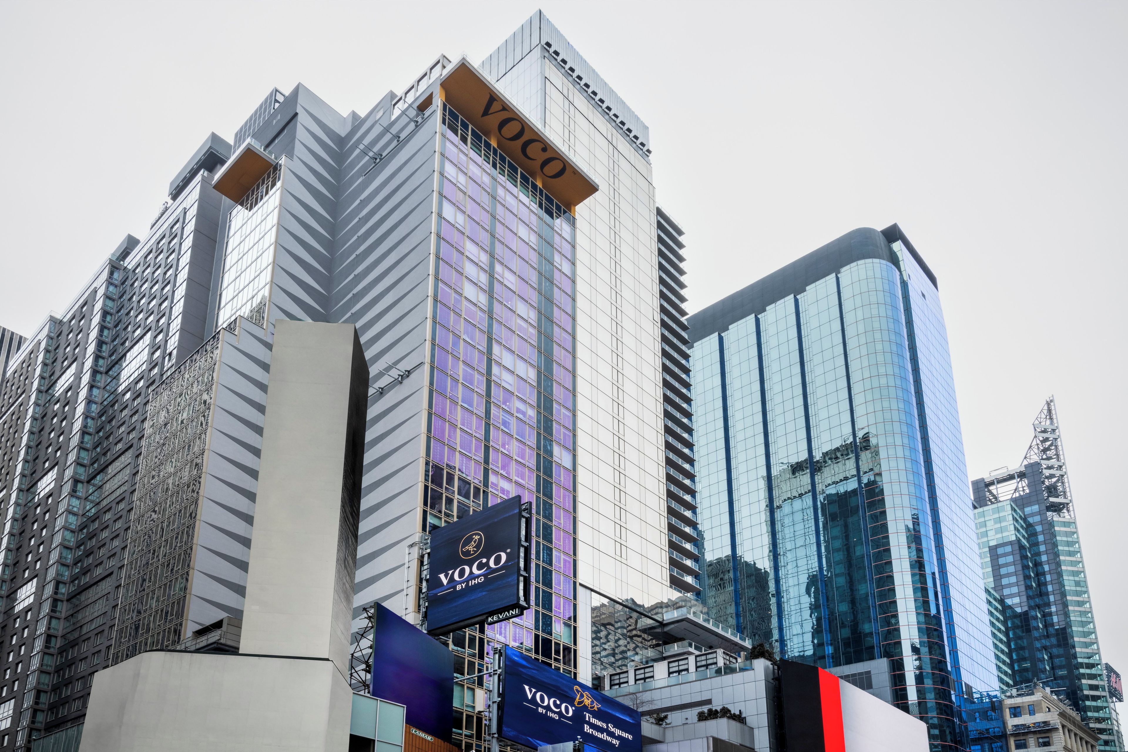 A high-rise building with 'VOCO' signage, modern architecture, and reflective glass windows.
