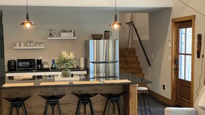 A modern kitchen with a central island, bar stools, a refrigerator, and pendant lighting. - Nash’s cabin in Leitchfield that is Pet Friendly, WIFI, w/ Creek. (Leitchfield)