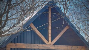 A rustic cabin with a covered porch, large windows, and a stone foundation. - Nash’s cabin in Leitchfield that is Pet Friendly, WIFI, w/ Creek. (Leitchfield)