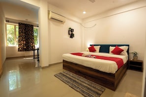 A modern bedroom with a large bed, a bedside table, an air conditioning unit, and a view of the outdoors. - Morjim Sea Waves (Morjim)