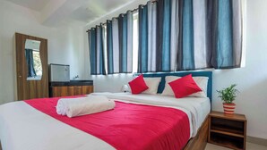 A neatly made bed with red and white bedding, a small bedside table with a potted plant, and a mirror on the wall. - Morjim Sea Waves (Morjim)