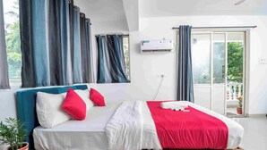 A bedroom with a bed, curtains, an air conditioning unit, and a view of the outdoors. - Morjim Sea Waves (Morjim)