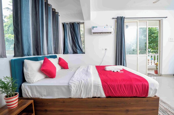 Un dormitorio con cama, cortinas, aire acondicionado y vistas al exterior.