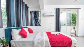 Une chambre à coucher avec un lit, des rideaux, un appareil de climatisation et une vue sur l’extérieur.