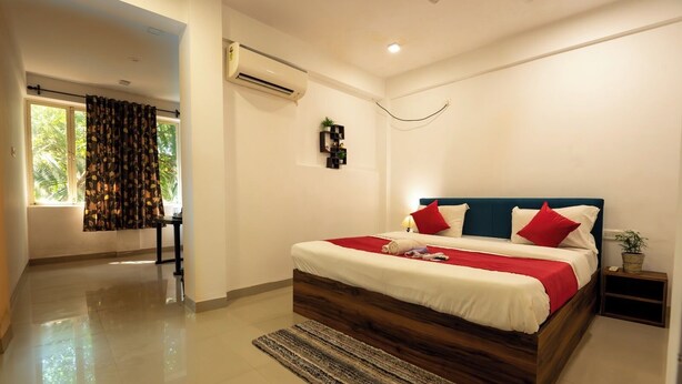 Une chambre moderne avec un grand lit, une table de chevet, un appareil de climatisation et une vue sur l’extérieur.