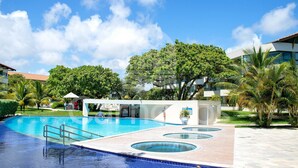 Una piscina con solárium, rodeada de vegetación y edificios modernos.