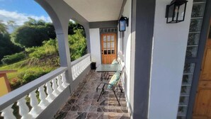 A covered porch with a stone floor, a wooden door, and a table with chairs. - Visconti Guest House (Cottage)