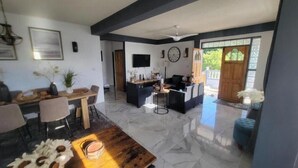 A spacious living area with a dining table, sofas, and a TV. - Visconti Guest House (Cottage)
