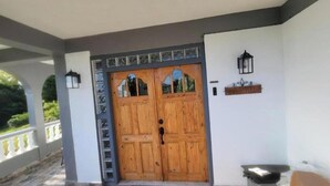 A wooden double door with a black handle, a small black lantern on the wall, and a white mailbox. - Visconti Guest House (Cottage)