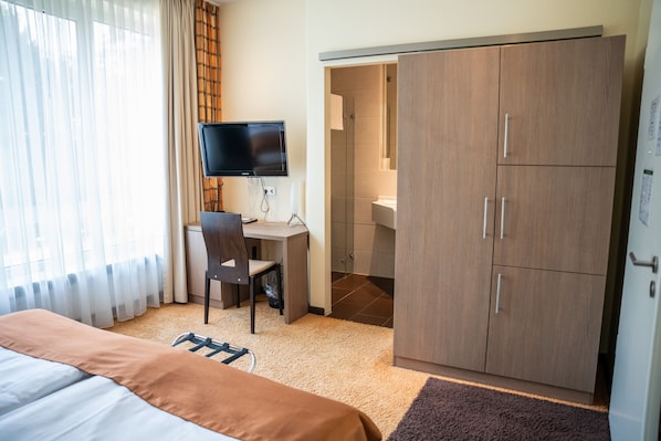 Une chambre d’hôtel comprenant un lit, un bureau avec une chaise, une télévision et une armoire.