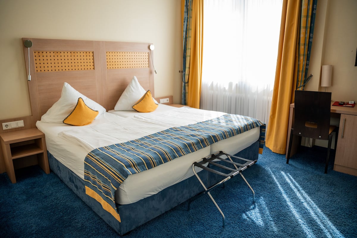 A hotel room with a bed, a desk, and a chair.