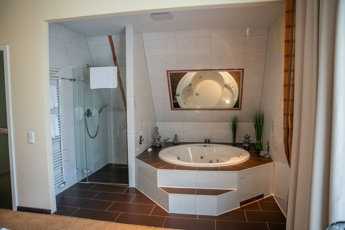 A modern bathroom with a glass-enclosed shower, a freestanding bathtub, and a large mirror above the sink.
