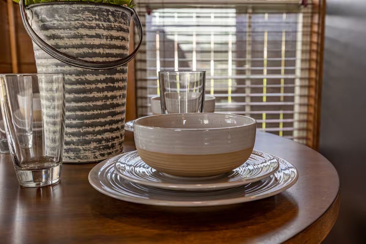 A dining table with a bowl, plates, and glasses.