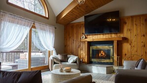 A cozy living room with a fireplace, comfortable seating, and a large TV.