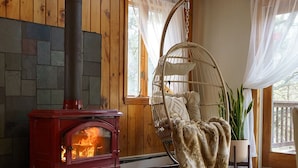 A cozy room with a wood-burning stove, a rocking chair, and a large window.