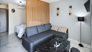 A modern living room with a grey sectional sofa, a black marble coffee table, and a wooden slat partition.
