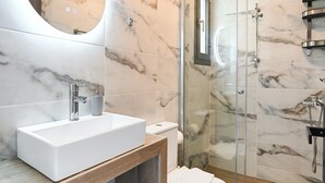 A modern bathroom with a white sink, a toilet, and a glass-enclosed shower.