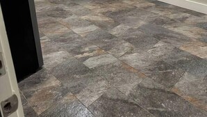 Una habitación con piso de baldosas, una puerta blanca, un armario con repisas y un cuadro en la pared.