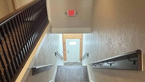 A wooden staircase with a handrail on both sides, leading to a door at the top.