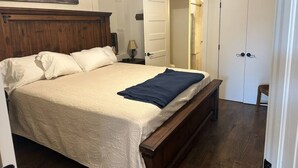 A bedroom with a wooden bed, a white door, and a painting on the wall.