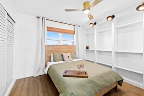 Enjoy a restful stay in this cozy room featuring a large bed, a wooden headboard, and a ceiling fan with lights.