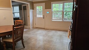 A dining area with a wooden table and chairs, a door with a window, and a view of trees outside. - Get cozy in this 2-bedroom garden apartment in peaceful Alpharetta. (Alpharetta)