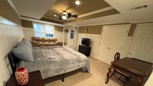 A bedroom with a bed, a dresser, a TV, and a door. - Get cozy in this 2-bedroom garden apartment in peaceful Alpharetta. (Alpharetta)