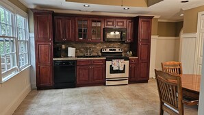 A kitchen with dark wood cabinets, a built-in oven, and a dishwasher. - Get cozy in this 2-bedroom garden apartment in peaceful Alpharetta. (Alpharetta)