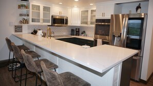A modern kitchen with white cabinets, stainless steel appliances, and a marble countertop. - Magnificent, newly remodeled Snowmass Condo (Snowmass Village)