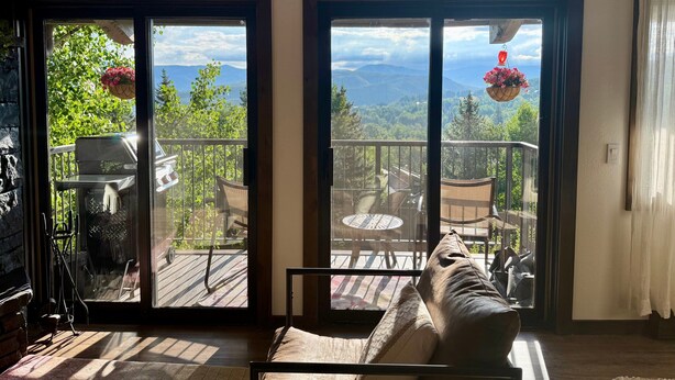 A room with a large sliding glass door leading to an outdoor deck with a view of mountains and greenery. - Magnificent, newly remodeled Snowmass Condo (Snowmass Village)
