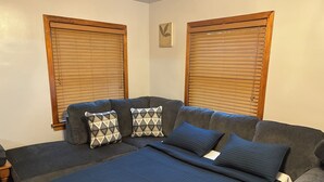 Una habitación con un sofá modular, dos cojines estampados y una manta azul.