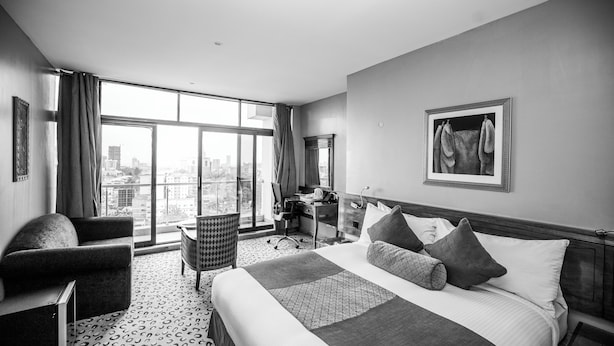 Une chambre d’hôtel moderne, dotée d’un grand lit, d’un bureau et offrant une vue sur la ville.
