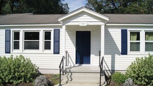 Un bâtiment blanc avec une porte et des volets bleus, une plaque portant le numéro 507 au-dessus de la porte, et un petit escalier menant à l’entrée.