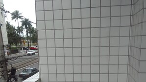 Esquina de una habitación con paredes de azulejos y un tendedero de metal.