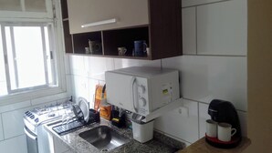 Una cocina con microondas integrado, cafetera y lavamanos.